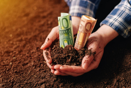 肥沃的土壤及欧元钱钞的双手