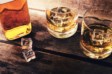 瓶威士忌和冰暗木制的桌子上的眼镜