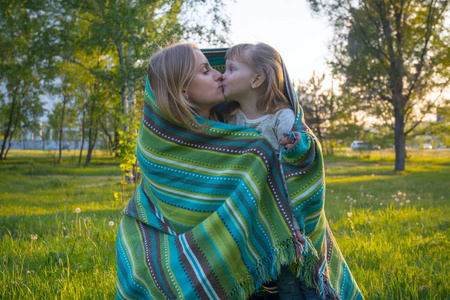 幸福的母亲和小女儿，裹在毯子里，吻