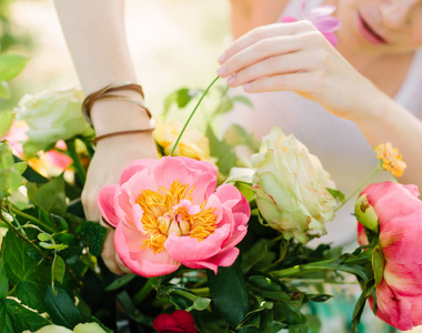 花束，假日 人和插花概念紧靠束美丽的粉红色夏威夷珊瑚牡丹和白玫瑰，一个年轻女孩花店在白色工作的妇女设计者的手里