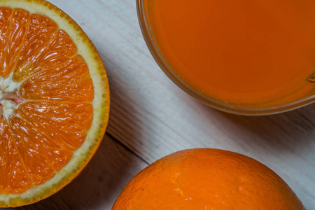 一杯新鲜的橙汁与橙子片木制的桌子上。鲜桔子汁的制备