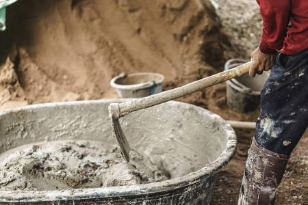 亚洲工人用锄头与沙子混合水泥粉