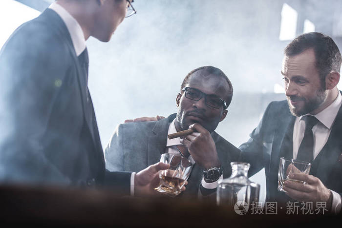 多族裔群商人花时间在一起喝的威士忌和吸烟,多元文化业务团队