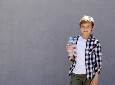 金发男孩喝干净的水。健康的生活方式