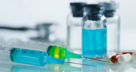 宏拍摄的两个注射器在实验室与有色液体疫苗为儿童或老年人或治疗疾病。概念 疾病 医疗服务 科学 麻醉 安乐死和糖尿病