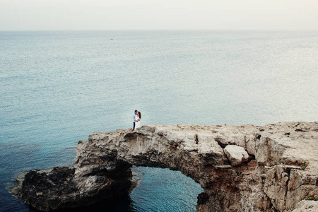从远处看看美丽的夫妇站在岩石上