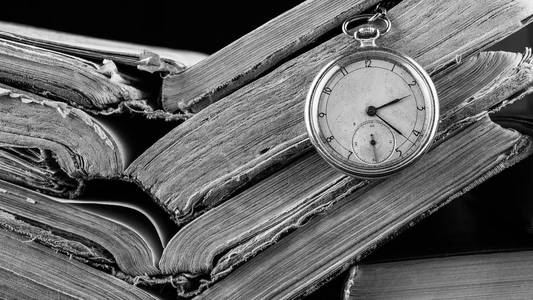 腐朽的破旧明智旧书背景上的时钟。黑白摄影