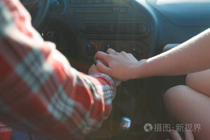 照片 一对年轻夫妇手牵手坐在车里, 穿着衬衫和短裤.