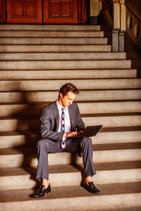 笔记本电脑，坐在楼梯上工作的美国商人