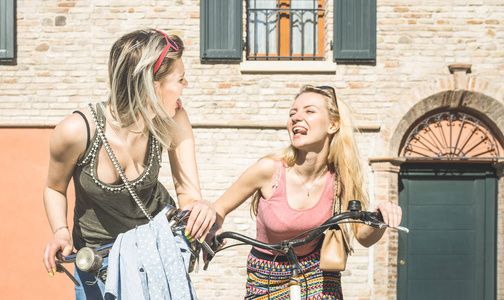 开心快乐的女性朋友夫妇骑着自行车在城市旧城友谊概念与年轻女友在夏天一起骑自行车的有趣态度春天时间明亮下午口气筛选器