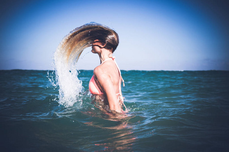 美丽的年轻的女人在清爽的海水中享受乐趣。巴厘岛