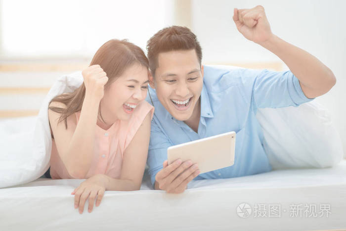 幸福的家庭,亚洲夫妻情侣享受欢呼起来和观看足球体育赛事现场直播