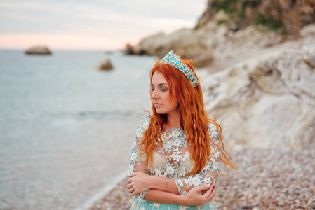 年轻女子在豪华的礼服站在亚德里亚海的岸边