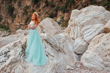 年轻女子在豪华的礼服站在亚德里亚海的岸边