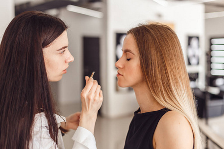 年轻女子 cosmetologistt weezing 模型在美容院的眉毛