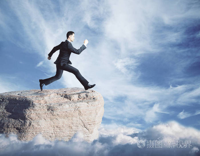 年轻的商人在天空背景上跳下悬崖的侧面图.成功的概念