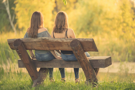 两个美丽的女人坐在长椅上和放松