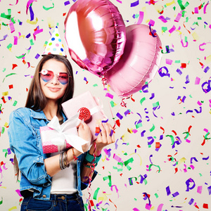 美丽微笑的女人，与粉红色的气球 礼品和纸屑