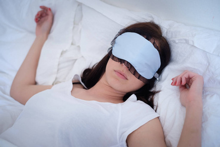 轻松的女人睡在她床上，戴着面具