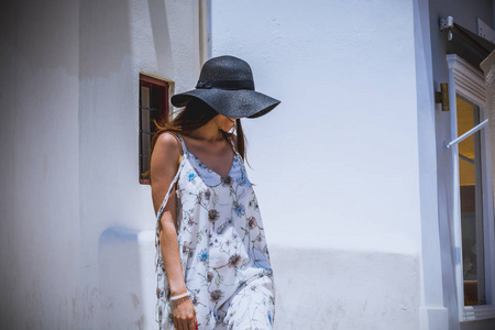 女人旅游度假，在圣托里尼岛伊亚的街道上漫步。在前往著名的白色村庄与地中海和蓝色圆的白色衣服的人