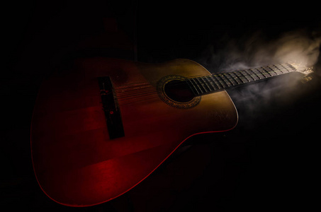 音乐概念。木吉他在黑暗背景下的束光与烟与副本空间上分离。吉他弦，关闭。选择性的焦点。火烧效应