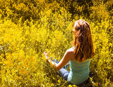 在城市公园在黄色的花，夫人被从事冥想。美丽的女人，在公园里做瑜伽冥想