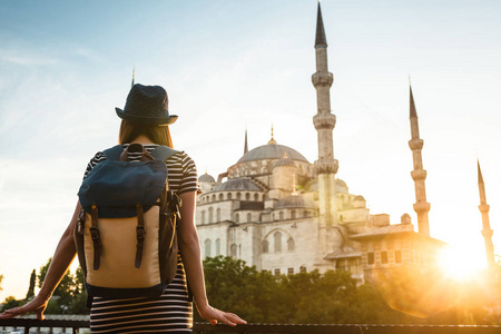 旅行者年轻漂亮的女孩在看着一个蓝色清真寺伊斯坦布尔著名的旅游胜地，背包里的一顶帽子。旅游 观光 观光