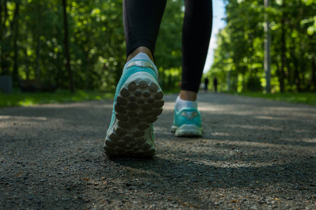 在公共公园的道路上关闭跑步者脚的鞋。妇女健身慢跑锻炼健康概念