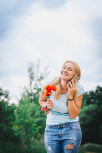 金发白种人女人拿着花，在花园里谈论智能手机