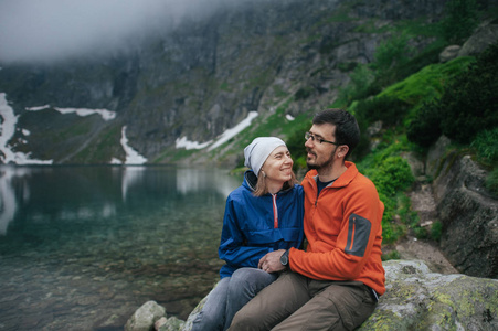 旅行者夫妇坐在湖附近的岩石