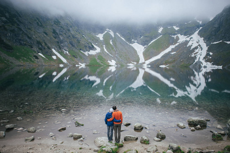 旅行者夫妇站在湖附近的岩石