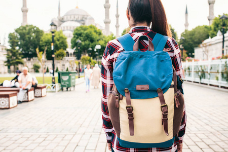 年轻漂亮的女孩旅行背包里，看着蓝色清真寺伊斯坦布尔著名的旅游胜地。旅游 观光 观光