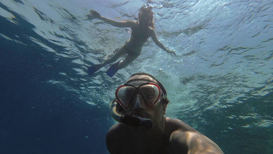 浮潜。一个男人和一个女孩在带着面具海里游泳