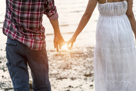 年轻对浪漫的情侣站在海滩上牵手
