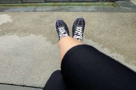 运动紫罗兰运动鞋, 年轻的女性跑鞋在水泥背景