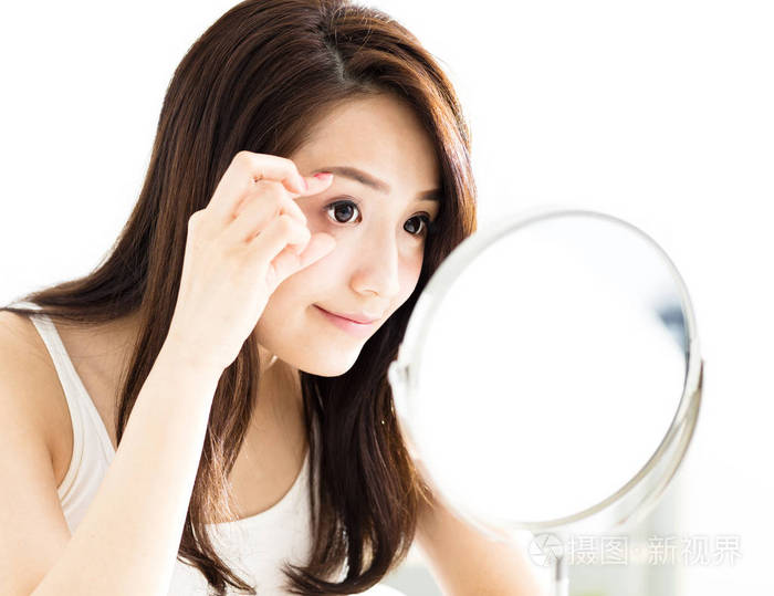 年轻女人照镜子和检查眼睛