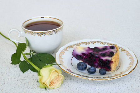 在盘子里，喝杯茶，在白色的背景白玫瑰蓝莓派关闭