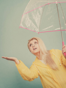 女人穿着雨衣打着伞检查天气图片