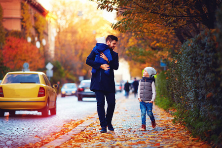 父亲带孩子们走在秋天城市街道