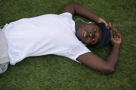 累了非洲裔美国男性运动员艰苦训练后躺在草地上
