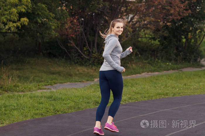 开朗的运动型女人在日出在公园跑步