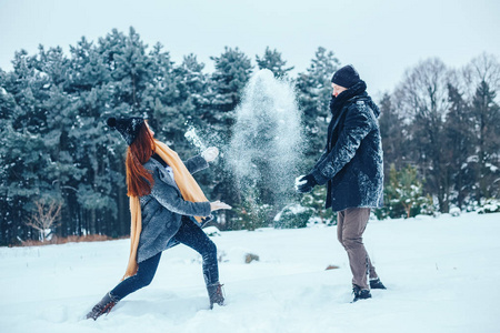 男孩和女孩在冬季树林里休息。丈夫和妻子在雪地里。年轻夫妻在冬季公园散步