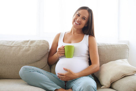 怀孕的女人坐在一起喝杯茶坐在沙发上