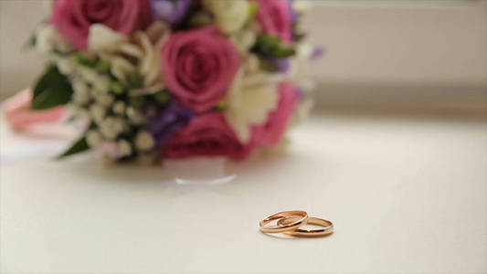 结婚戒指和玫瑰。婚庆首饰和戒指。美婚戒的框中。金色的结婚戒指