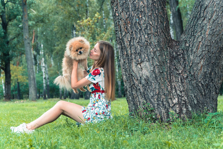 一个女孩走着一个公园，一只狗。博美犬施皮茨