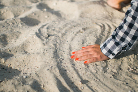特写手释放掉砂。沙子在蓝色的海洋中流经手中。夏季海滩度假概念