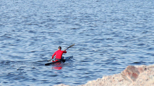 一个穿着红色夹克的人驾驶皮划艇