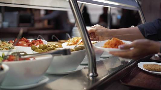 年轻女子把食物放在食物上的盘子里