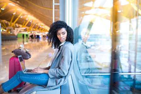 在机场等在窗口使用笔记本电脑的黑女人