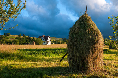 乡村景观与干草堆在夏天晴朗的一天。农村山风景用暴风云